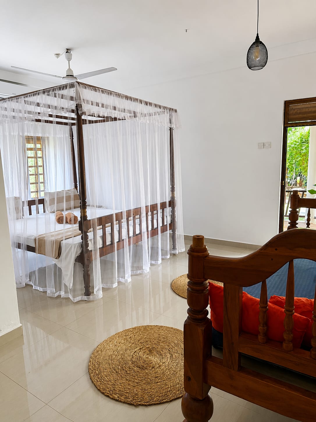 Airy bedroom with canopy bed, woven rugs and a door opening to the garden terrace